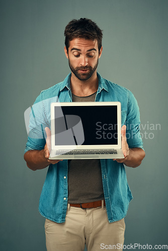 Image of Man, laptop and mockup screen for advertising or marketing against a grey studio background. Male person holding technology or computer display, mock up or copy space for branding or advertisement