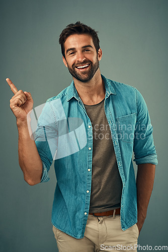 Image of Point, smile and portrait of happy man in studio on gray background for announcement, news and information. Fashion, mockup space and male person with hand sign for promotion, choice and branding