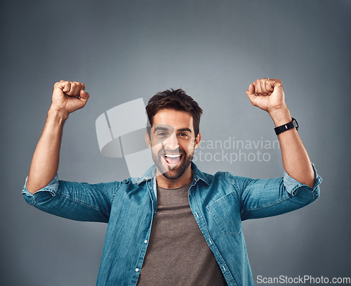 Image of Happy man, fist and celebration for winning, achievement or success against a grey studio background. Excited portrait of male person or winner in victory, win or accomplishment on mockup space