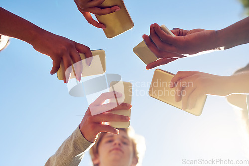 Image of Hands, below and phone by friends together for social media, networking and sharing app on blue sky background. Low angle, smartphone and gen z people with internet, addiction or online communication