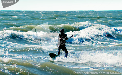 Image of Silhouette of a kitesurfer on waves of a sea