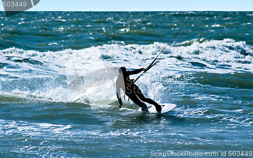 Image of Silhouette of a kitesurfer on waves of a sea