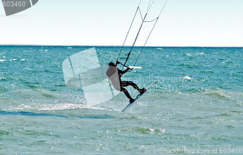 Image of Silhouette of a kitesurfer on waves of a sea