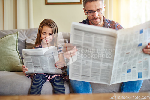 Image of Father, daughter and reading newspaper on sofa for knowledge, literature or news in living room at home. Happy dad, child and smile for family bonding, learning or education on lounge couch together