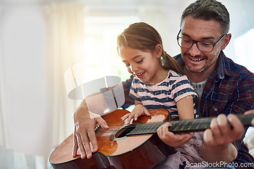 Image of Father, girl and learning guitar in home, bonding and having fun together. Dad, child and playing acoustic instrument, teaching or education for music lesson, smile and enjoying quality time in house