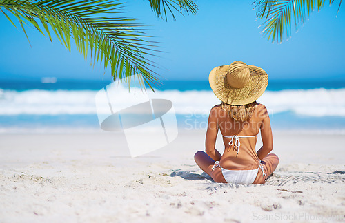 Image of Relax, back view of a woman on the beach and sitting on the sand, Summer vacation or holiday break, freedom or adventure and female person relaxing at the sea with blue sky for peace in nature