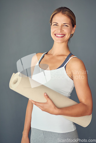 Image of Happy woman, yoga and portrait smile with mat for exercise, healthy wellness or workout against a grey studio background. Excited female person or yogi smiling for mindfulness, fitness or body health