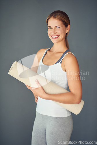 Image of Happy woman, portrait smile and yoga mat for exercise, healthy wellness or workout against a grey studio background. Excited female person or yogi smiling for mindfulness, zen fitness or body health