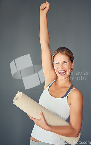 Image of Happy woman, portrait and yoga with fist in celebration for healthy exercise against a grey studio background. Excited female person or yogi with smile for winning, fitness or workout success at gym