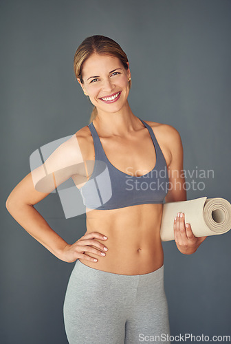 Image of Happy woman, fitness and portrait smile for yoga exercise, zen workout or healthy body against a grey studio background. Female person or yogi smiling with mat for spiritual wellness or mental health