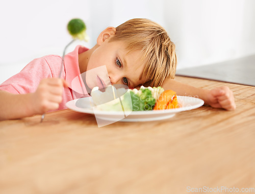 Image of Sad, hungry and a child with vegetables for dinner, unhappy and problem with food. Frustrated, diet and a little boy eating broccoli and carrots, disappointed with lunch and nutrition for youth