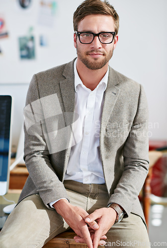 Image of Portrait, glasses and focus with a business man in the office for corporate or professional work. Face, eyewear and leadership with a young male manager sitting in a workplace on a blurred background