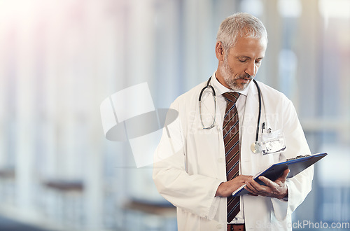 Image of Documents, healthcare and insurance with a senior doctor standing in a hospital corridor for treatment or diagnosis. Medical, trust and clipboard with a man medicine professional in a health clinic