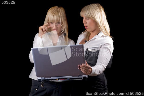 Image of Two young businesswomen with laptop. Isolated on black