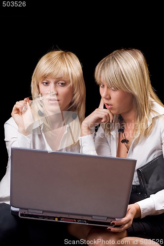 Image of Two young businesswomen sitting with laptop. Isolated