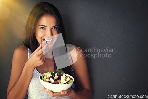 Image of Woman is eating a tomato from salad, portrait and healthy food with nutrition and vegetables on wall background. Happy, vegan and health, female model on diet to lose weight and mockup space