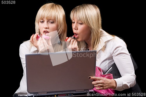 Image of Two blondes do makeup in front of the laptop screen