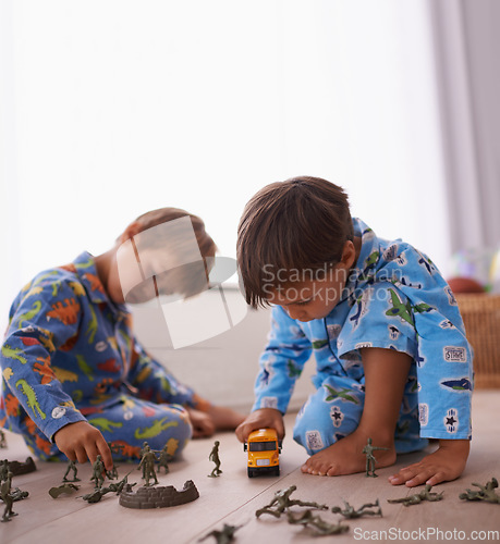 Image of Young boys, playing and toys together in pajamas for fun with miniature action figures, toy car or games. Brothers, sibling children and family bonding in playroom at home for learning or development