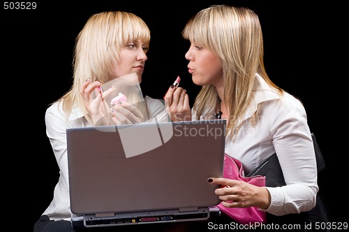 Image of Two blondes do makeup in front of the laptop screen. Isolated