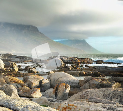 Image of Sea, rocks and landscape with beach and travel destination, waves and summer vacation in Cape Town. Environment, ocean view and seaside location with mountain and clouds, nature and adventure outdoor