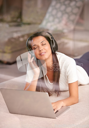 Image of Laptop, headphones and a woman listening to music on a home sofa with internet for streaming online. Happy female person relax on couch with tech to listen to audio, radio or podcast for peace