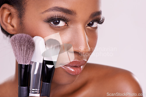Image of Skincare, makeup brushes and portrait of black woman with brush on face in studio with cosmetic application tool. Skin care, blush and cosmetics, beauty model with luxury powder on pink background.