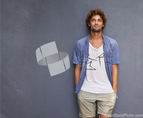 Image of Confidence, casual and male model by a wall with mockup space with a hipster, cool and stylish outfit. Happy, positive and handsome man with trendy style or fashion by a gray background with mock up.