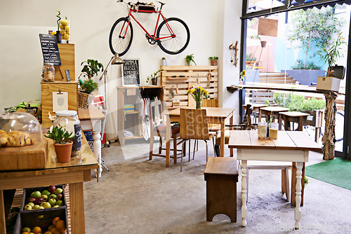 Image of Empty, coffee shop and interior space with table, chairs and furniture or small business, bistro and cafe with unique design and style. Background, creative startup and food store with bike on wall