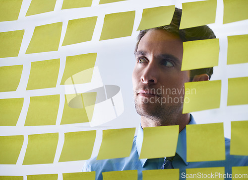 Image of Businessman, face and thinking in planning, sticky note or brainstorming tasks on glass board at office. Thoughtful man contemplating business decision, strategy or schedule in wonder at workplace