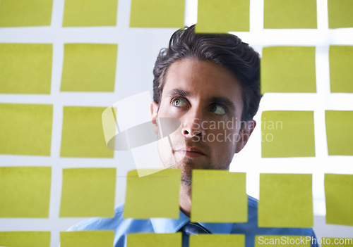 Image of Creative man, face and thinking for sticky note, brainstorming or planning tasks on glass board at office. Male person in problem solving, idea strategy or solution for startup decision at workplace