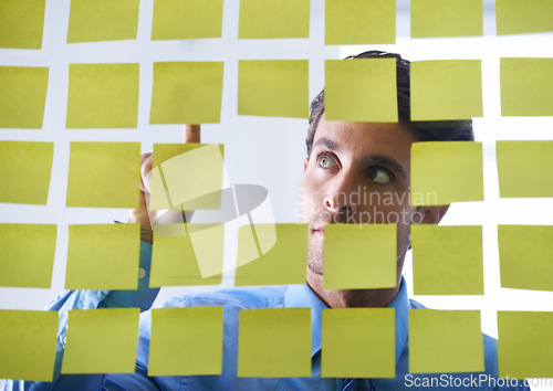 Image of Creative man, face and thinking, pointing to sticky note in schedule brainstorming or planning tasks on glass board. Thoughtful male contemplating business startup or strategy in wonder at the office