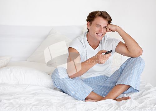 Image of Man, space and watching tv in bedroom with happiness, remote and morning for streaming, entertainment and relax. Happy young male person enjoying television series, news and control for choice in bed