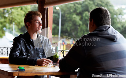 Image of Men, friends and drinking beer at a pub and restaurant with conversation and discussion. Alcohol, guys and young people together at diner with alcohol and drink with bottle and cigarette at table