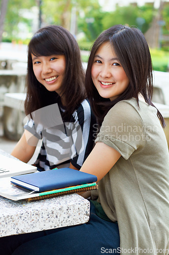 Image of University, smile and portrait of girl students with scholarship sitting outdoor on campus for education. Knowledge, happy and Japanese female college friends bonding in a park or garden with books.