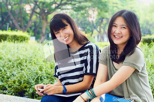 Image of University, nature and portrait of girl friends with scholarship sitting outdoor on campus for education. Knowledge, smile and female college students in park for fresh air studying for test or exam.