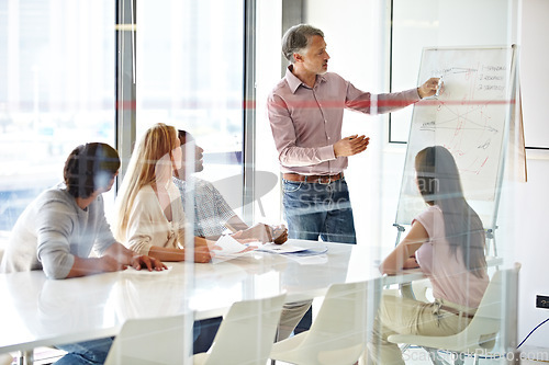 Image of Planning, mature mentor with colleagues and chart in a boardroom of their modern workplace. Teamwork or collaboration, data review or brainstorming and coworkers working together in business meeting