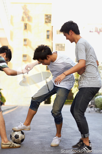 Image of Friends in city street playing soccer together for sports, fun and happy energy with urban games in Korea. Ball game for teen friendship, group of people in road with football, weekend in community.