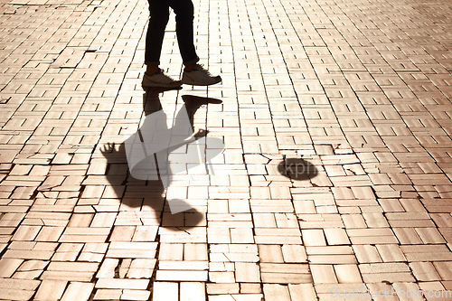 Image of Sports, soccer and man shadow with a ball training for a skill, trick or stunt on a pavement. Silhouette, football and legs of a male person practicing for a game, match or tournament in the city.