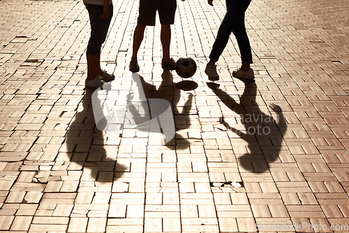 Image of Sports, football and shadow of friends with a ball training for a skill, trick or stunt on a pavement. Silhouette, soccer and legs of people practicing for a game, match or tournament in the city.