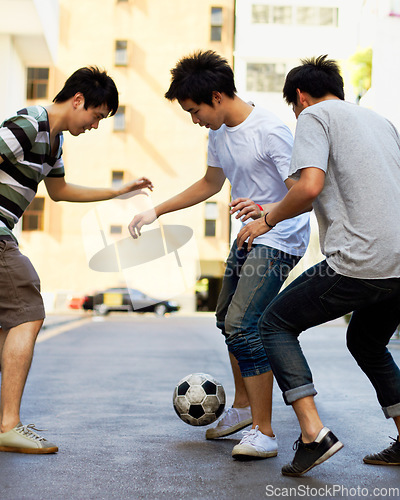 Image of Friends in street playing football together for sports, fun and happy energy with urban games in Korea. Games for kids, friendship and teen group in road with soccer ball, weekend time in Asian city.