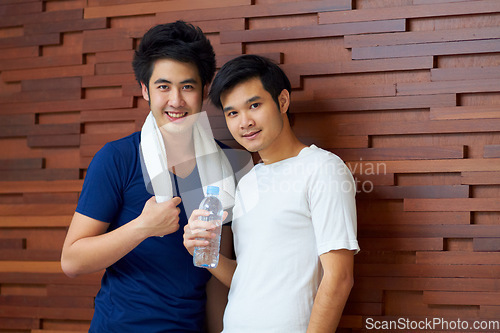 Image of Happy, portrait and gay couple at the gym with water on a break from a workout together. Smile, wellness and Asian lgbt men training at a club for exercise, health and happiness with fitness