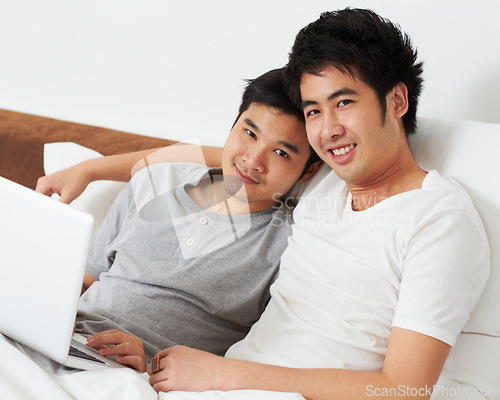 Image of Portrait, laptop and bed with a gay couple watching a movie together while bonding in the morning. Love, happy or smile with an lgbt man and partner lying in their bedroom to relax while streaming