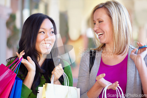 Image of Happy, sale and women with bags from shopping in the city or mall and excited about a deal. Smile, conversation and diversity with female friends talking while at a shop for clothes and fashion