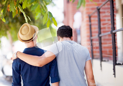 Image of City, travel and back of gay couple walking together in the street while on a tourism vacation. Love, affection and male friends embracing in an outdoor urban road while on a weekend trip or holiday.