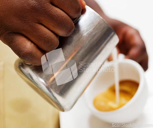 Image of Hands, coffee and a barista pouring milk into a cup while working in a cafe for hospitality or service. Kitchen, beverage and caffeine with a waitress in a restaurant to prepare a drink closeup