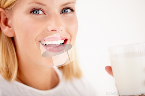 Image of Portrait, milk and happy with a woman drinking from a glass in studio isolated on a white background. Smile, nutrition or calcium with a healthy young female enjoying a drink for vitamins or minerals