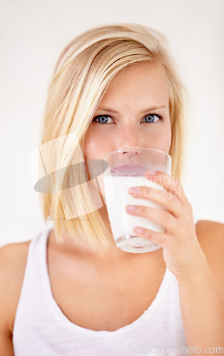 Image of Portrait, milk and a woman drinking from a glass in studio isolated on a white background. Health, nutrition and calcium with a young female enjoying a drink for natural vitamins in the morning