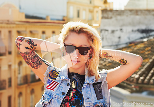 Image of Tattoo, portrait and fashion woman with sunglasses in city, urban body art and stylish outdoor. Face, rooftop and edgy female person from Canada in cool denim clothes, jacket or serious punk attitude