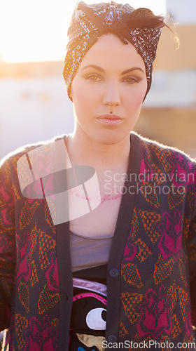 Image of Portrait, fashion and serious woman in city with scarf on head, urban tattoo and stylish. Face, street and trendy female person from Norway in cool clothes, attitude and body art outdoor at sunset.