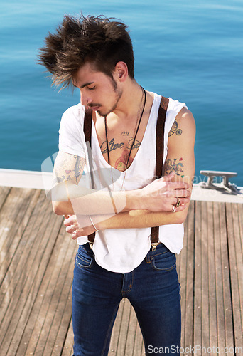 Image of Punk dress code, man with tattoos and on pier outdoors at the beach. Health wellness, travel or journey and male fashion model with tattoo ink on his body outside of the sea for nature fresh air